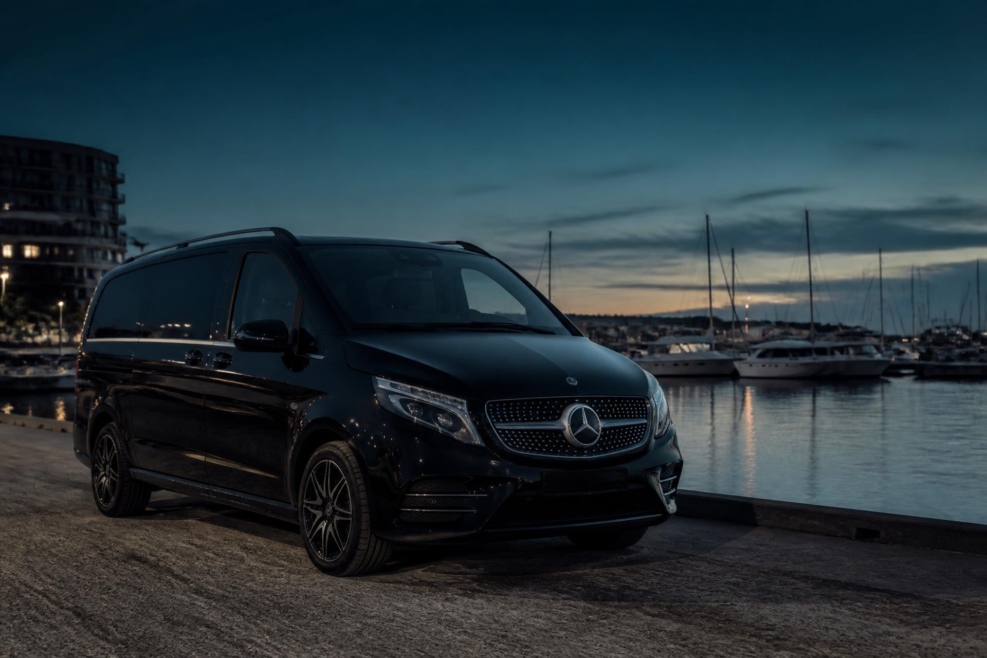 A black Mercedes V-Class parked on the quayside beside Poole Harbour at dusk